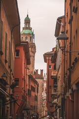 Terracotta-colored buildings and a green dome on a street near Piazza Maggiore, Bologna, Italy © Massimiliano