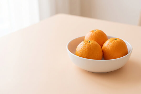Fresh oranges in white ceramic bowl on peach background