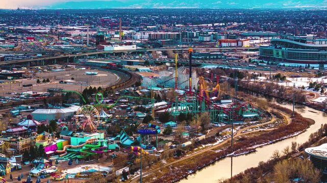 Aerial view of Elitch Gardens Theme Park with roller coasters and water slides near the South Platte River and urban infrastructure in Denver, Colorado, United States.