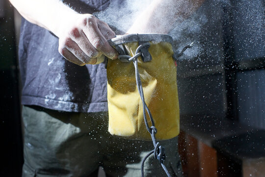 Athlete hand covering in chalk powder for climbing