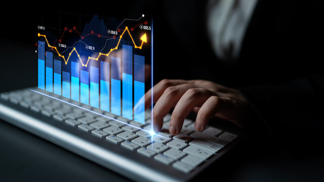 Digital workspace showcasing a businessman analyzing financial data with stock market graphs emerging from a keyboard, highlighting modern data-driven strategies. Scalp