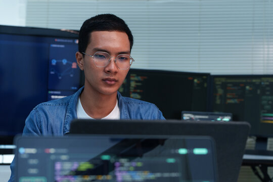 Programmer Developing Digital Software with Code on Multiple Screens