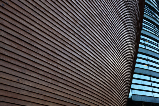 Abstract architectural detail of a contemporary building featuring a sweeping curved facade clad in horizontal wooden slats