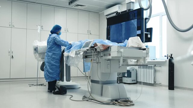 Doctor performing a catheter procedure under angiography and X-ray guidance in a modern interventional hospital operating room.