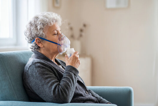 Senior woman using nebulizer treatment at home with copy space for respiratory healthcare.