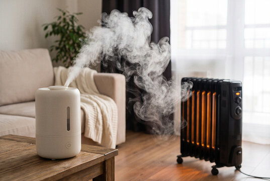 Humidifier releasing mist beside electric heater in cozy living room during dry winter weather.