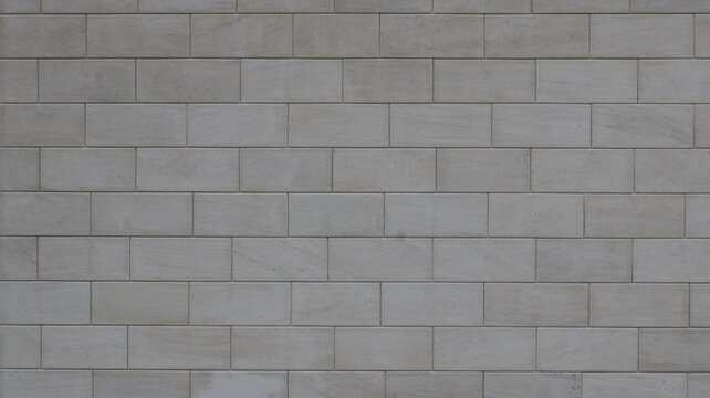 Close-up texture of a smooth, light-gray block wall. Uniform masonry made of rectangular stone or concrete blocks with neat joints. A minimalist, clean background for architectural design.