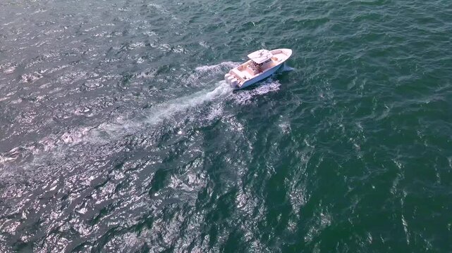 Aerial rear tracking view follows a white boat leaving a narrow foamy wake.

