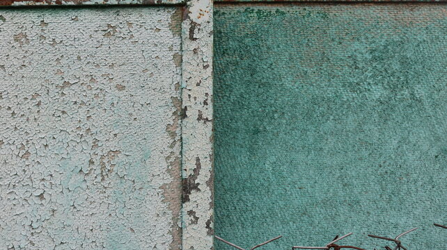 Texture of old painted metal and painted pressed wood. Peeling green and turquoise paint with chips, rust, and cracks. Design background featuring the vintage texture of a weathered iron surface.