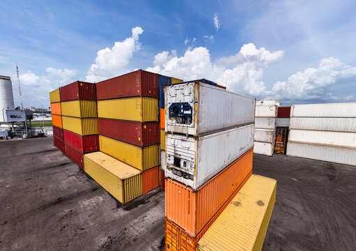Stacked shipping containers and reefer units in port container yard, wide angle