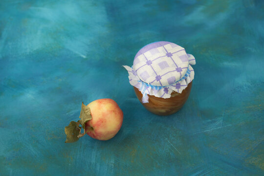Home cooking. An apple and a jar of apple jam on a blue background. Top view.