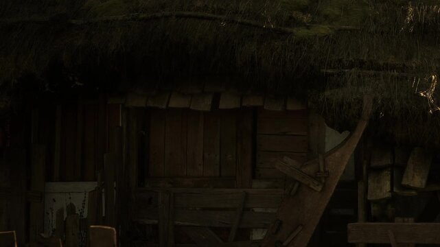 The barn shows wooden walls and structures under a thatched roof. The setting is rural and captures the essence of a vintage barn during the evening light.