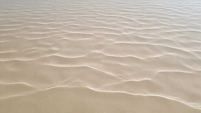 Close-up of a sandy surface. the sand appears to be light beige in color and has a smooth texture. the surface is rippled and uneven, creating a wave-like pattern.