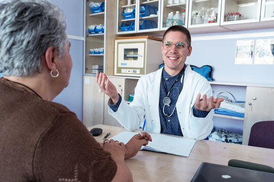 Doctor talks with an older female patient during a medical consultation. They discuss her health while the doctor listens carefully and provides guidance.
