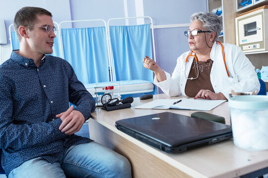 A patient is consulting with an experienced senior female doctor in her medical office, discussing their health and treatment options. The doctor listens carefully and explains the situation.