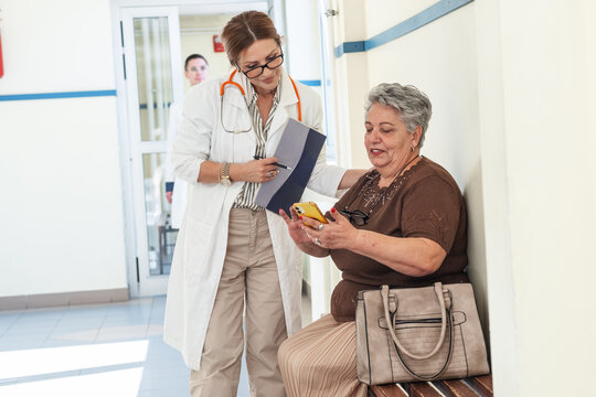 A female doctor talks with a patient who is waiting in the hospital hallway for their appointment. The conversation feels calm and friendly as they discuss the upcoming examination.