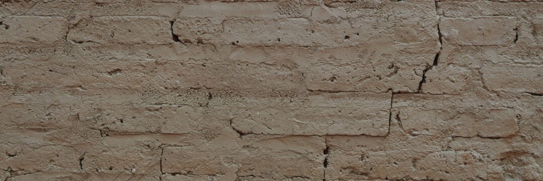 Old mud brick wall showing cracks and rough textured surface