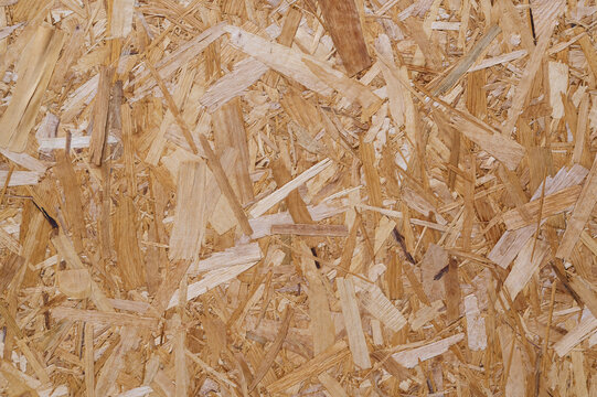 Close-up of OSB board with overlapping wood strands in brown tones.