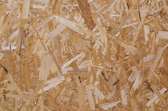 Close-up of OSB board with overlapping wood strands in brown tones.