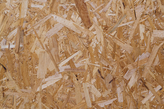 Close-up of OSB board with overlapping wood strands in brown tones.