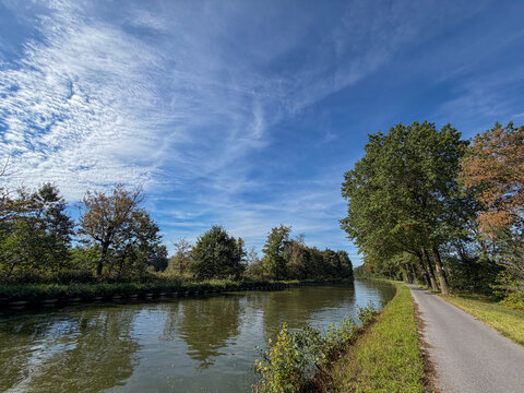 Scenic canal with tree-lined bike path under blue sky in Rijkevorsel, Belgi&euml;