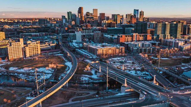 Aerial view of Denver skyline with highway interchange under golden hour light in Denver, Colorado, United States.