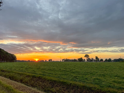 Dramatic sunset over rural meadow with wind turbines on horizon in Brecht, Belgi&euml;
