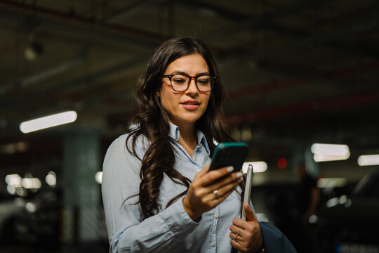 Woman using smartphone checking messages in parking garage