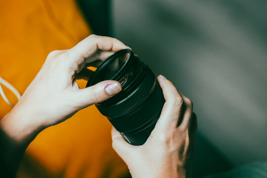 Hands attaching a filter to a camera lens, preparing photography gear for capturing images
