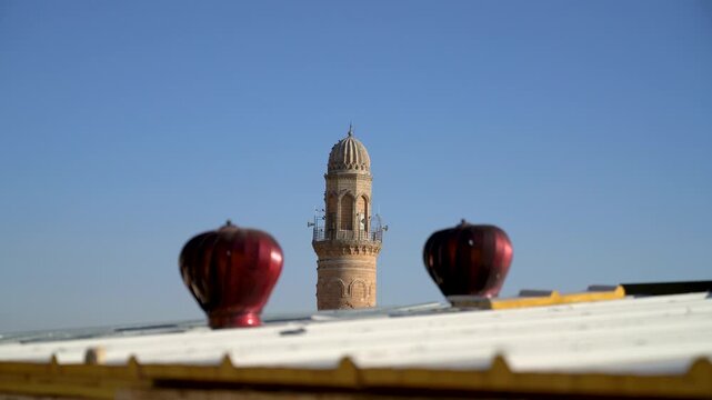 Ulu Cami minaret top, Great Mosque of Mardin, Turkey, seen between two red roof ventilators on a rooftop in the old town