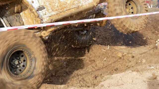 Off-road 4x4 buggy vehicle driving through deep mud pit spinning tires close up