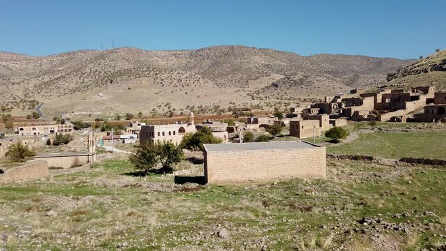 Dereici, also known as Killit, a Syriac village near Savur, Mardin, Turkey, stone houses, many in ruins, spread over a green hillside below dry hills