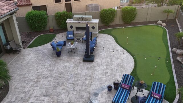 A 4k video of a desert landscaped backyard in Arizona featuring a travertine tiled pool deck, outdoor kitchen , spa and fireplace.