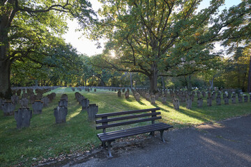 Obraz premium A serene wooden bench sits in a historic First World War cemetery in Nurnberg during autumn