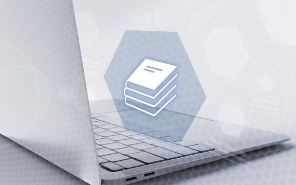 Una laptop moderna con un icono digital de pila de libros flotando en pantalla, representando la educaci&oacute;n online, el aprendizaje digital y el estudio virtual.