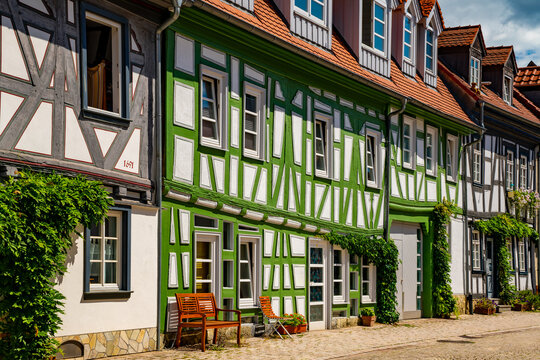 Colorful historic half-timbered houses along Weiherwiese in Idstein, Hesse, with traditional timber framing, cobblestones and lush greenery.