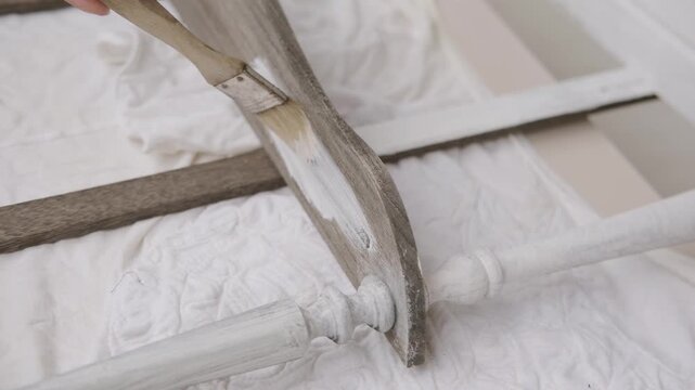 brush applying paint to old wooden furniture during furniture restoration, vintage bookcase restoration process, DIY home improvement and shabby chic style renovation project, hobby tool