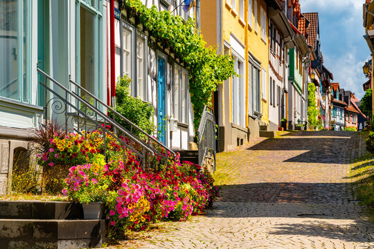 Flower-lined cobblestone street with colorful historic half-timbered houses in the old town of Idstein, Hesse, Germany.