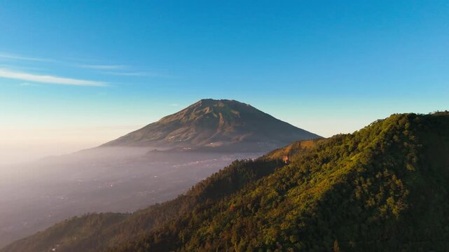 Aerial view of Mount Merbabu and Mount Telomoyo with lush green slopes and misty valleys in Getasan, Central Java, Indonesia.