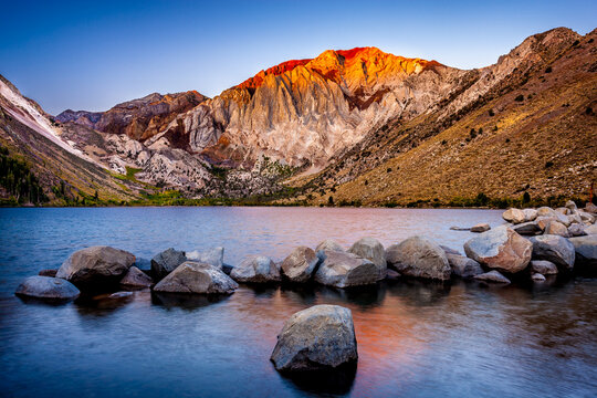Sun lights the mountain peak at dawn on Convict Lake in the Sierra Nevada mountains of California