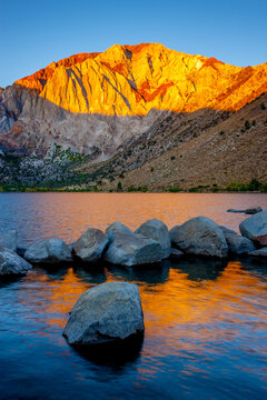 Sun lights the mountain peak at dawn on Convict Lake in the Sierra Nevada mountains of California