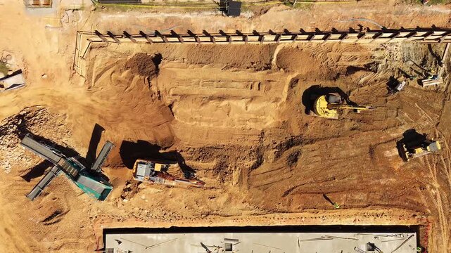 Aerial bird's-eye view of heavy equipment preparing a work site for building construction