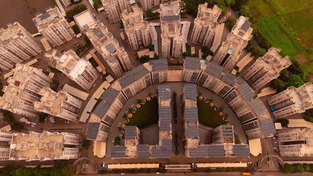 Aerial view of a large residential complex with curved high-rise buildings and rooftop solar panels in Surat, Gujarat, India.