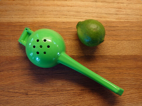 citrus juicer (squeezer) with lime on a wood cutting board