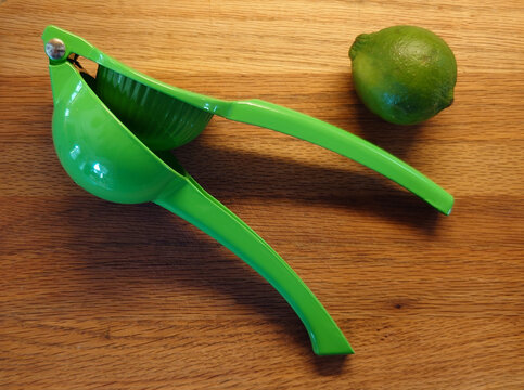 citrus juicer (squeezer) with lime on a wood cutting board