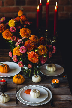 Fall table decoration with pumpkin composition. Family cozy thanksgiving dinner arrangement indoors, elegant wedding decor. Countryside style, candle light, autumn mood. Dark background
