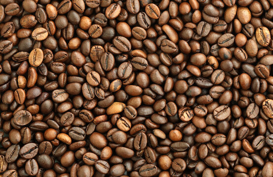 Detailed view on brown roasted coffee beans in big pile on table close up