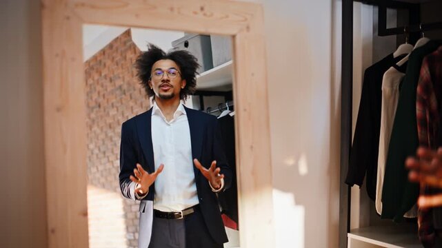 Shopper trying navy suit mirror. Man gesturing talking wardrobe dressing room.