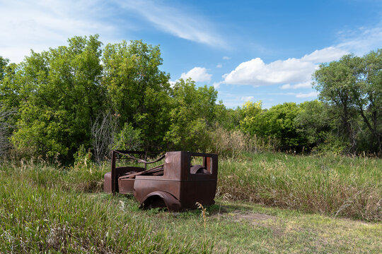 Rusty abandoned car in a field on a bright summer day