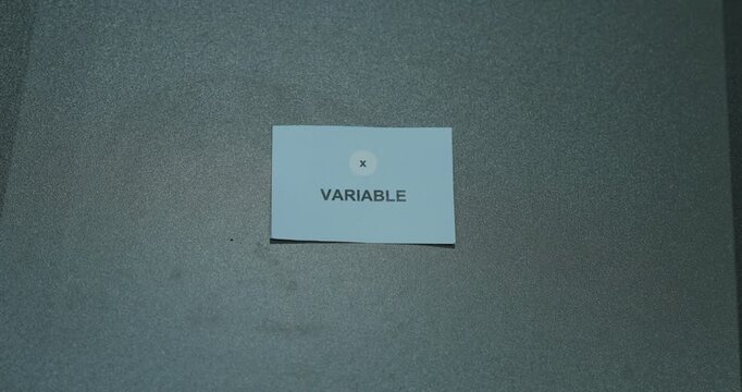 Variable text on a white paper card against a gray background, representing changing factors, data analysis and scientific concepts